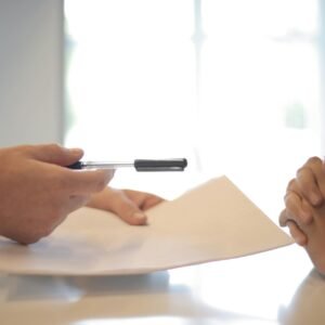Close-up of a contract signing with hands over documents. Professional business interaction.